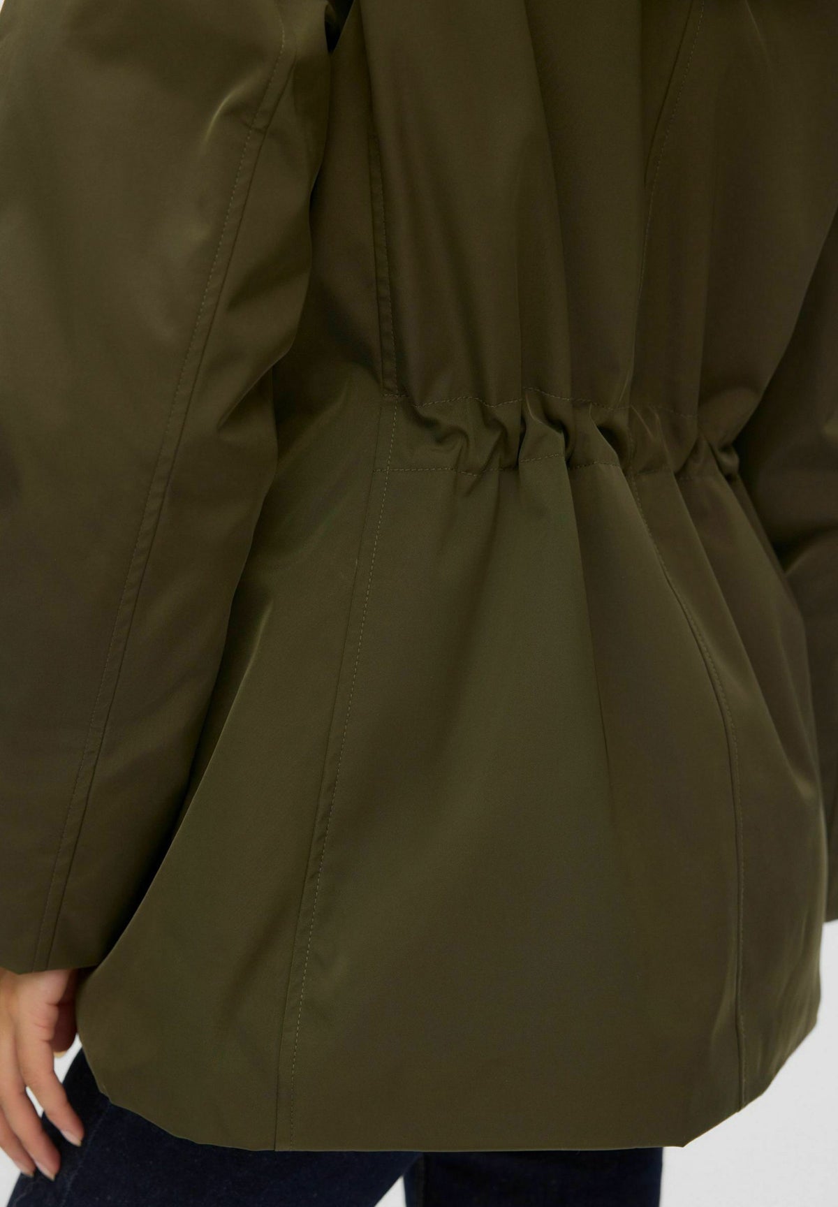 Ellen, mörkgrön parkas med huva, närbild på midjan