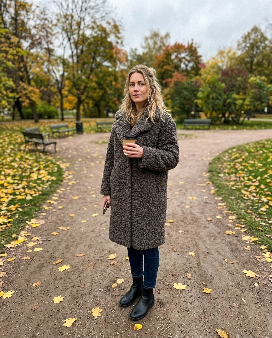 Alma, knälång kappa i lockig fuskpäls för dam i grå, stylinginspiration i en höstpark
