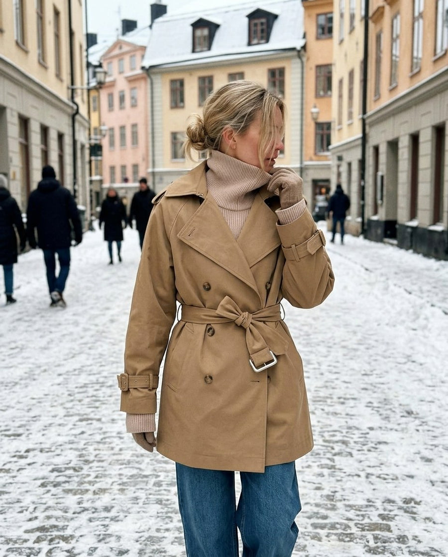 Elin, kort trenchcoat med skärp för dam i beige, stylinginspiration på en snöig gata