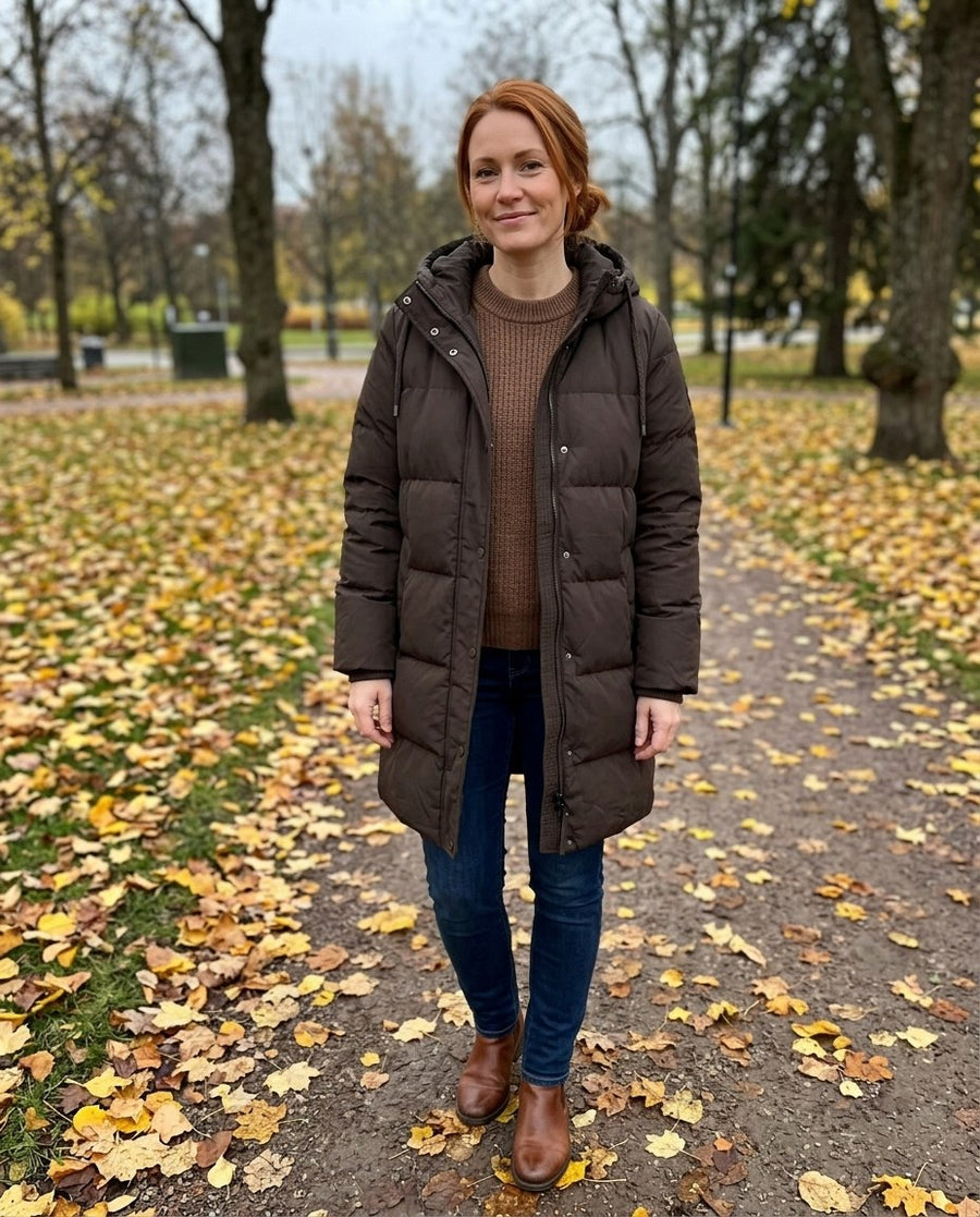 Tyra, lång vadderad jacka med huva för dam i brun, stylinginspiration i en höstpark