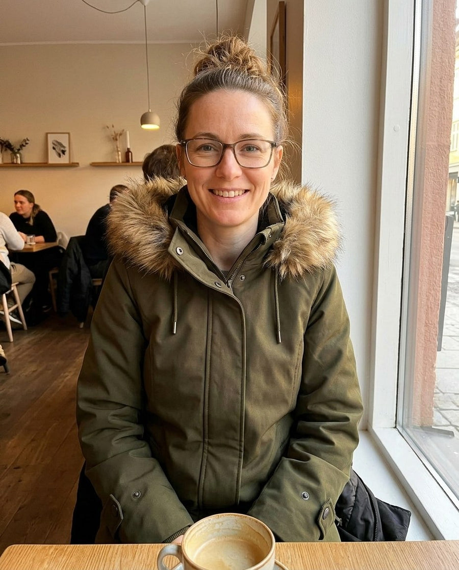Ellen, parkas med huva för dam i mörkgrön, stylinginspiration på ett kafé