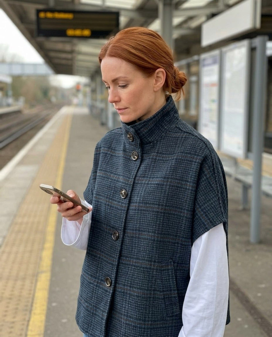 Liv, rutig cape i ullmix för dam i mörkblå, stylinginspiration på en perron