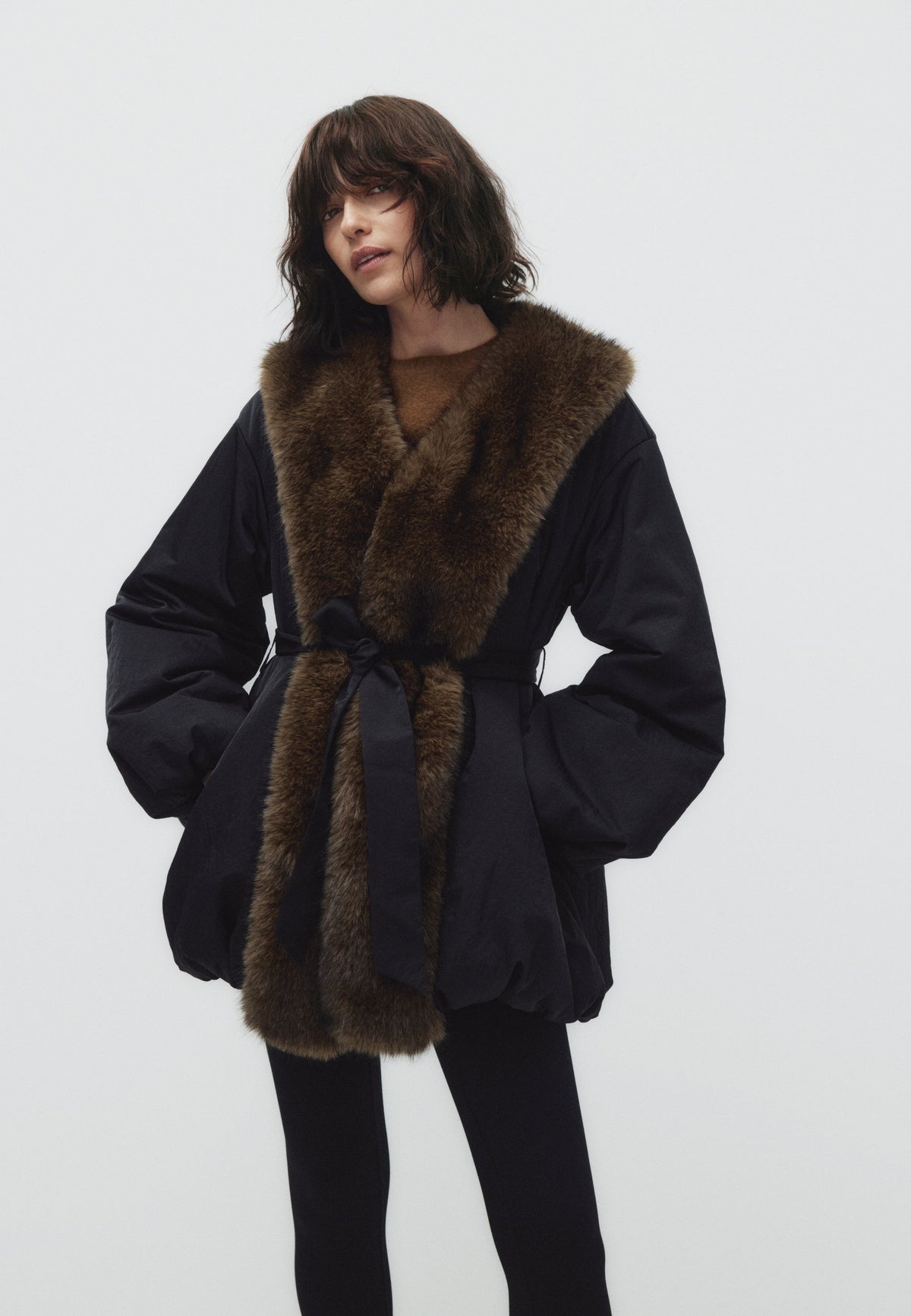 Tilda, wattierte Jacke in Schwarz mit Kunstfellkragen und Bindegürtel, von vorne