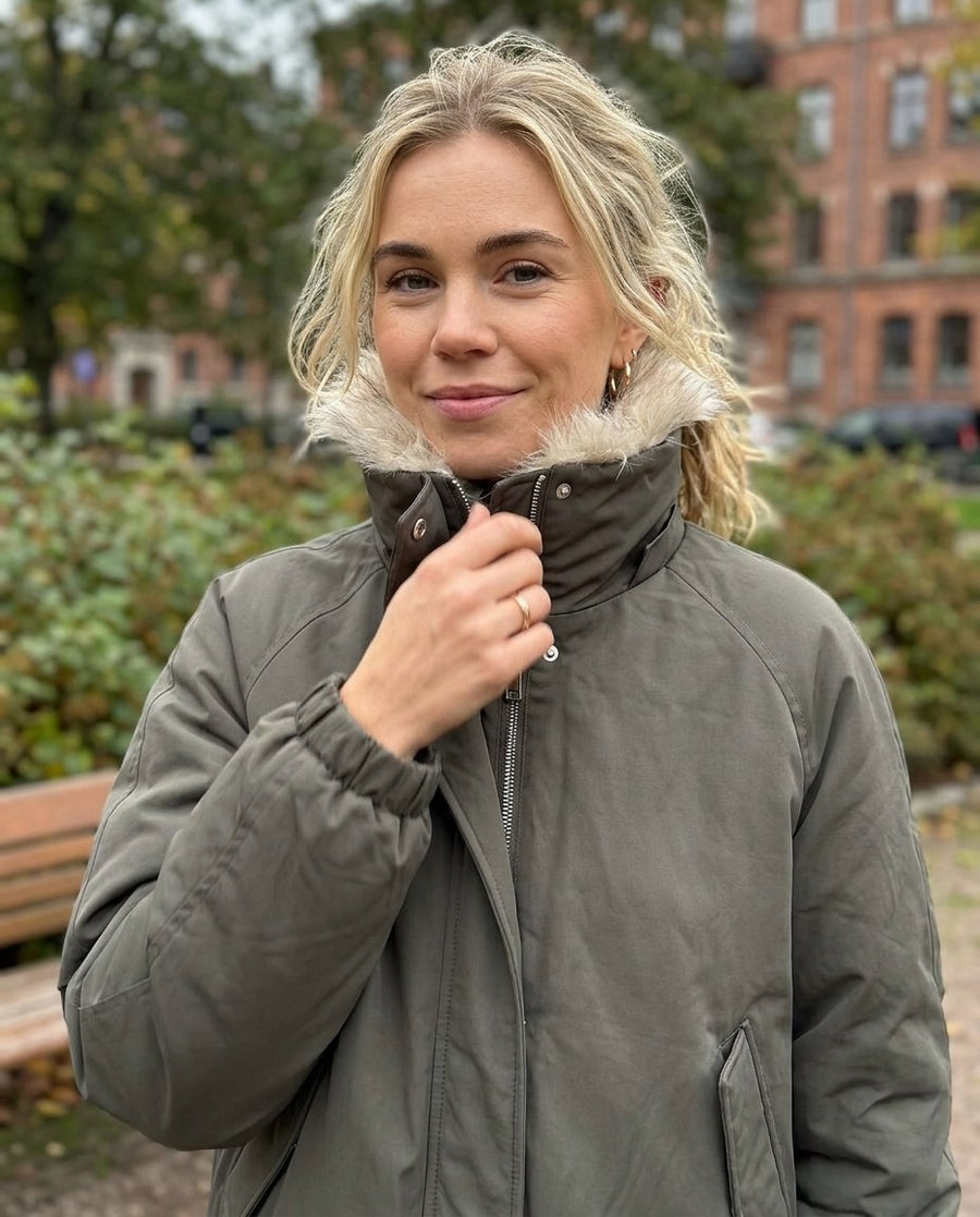 Svea, vadderad bomberjacka med hög krage för dam i mörk olivgrön, stylinginspiration närbild på materialet